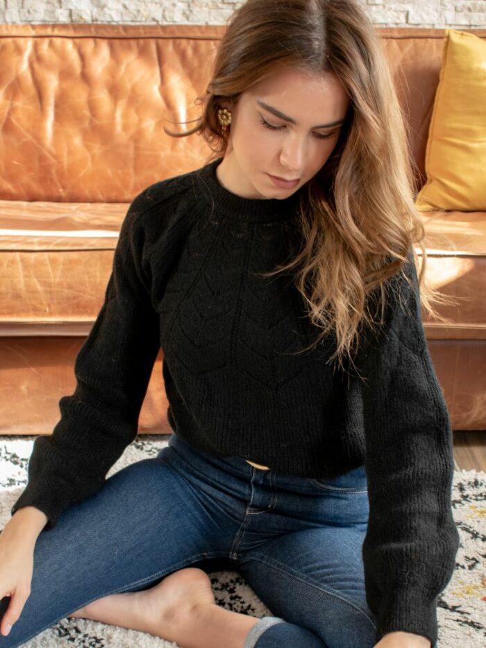 femme assise portant un pull noir en laine douce