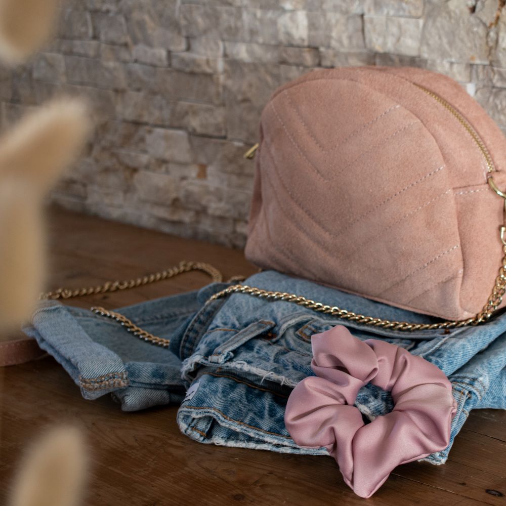 sac en cuir rose poudré posé sur un meuble