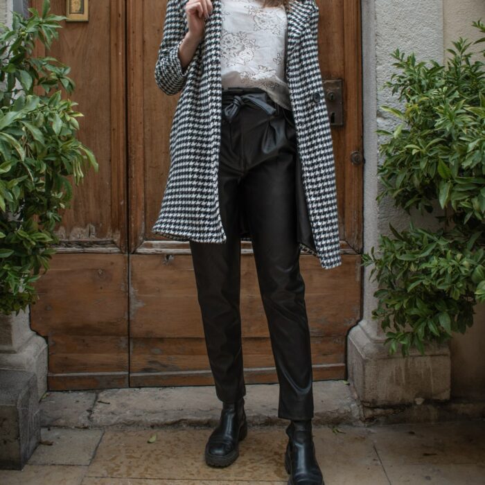 femme portant un pantalon paper bag en simili cuir et un manteau long